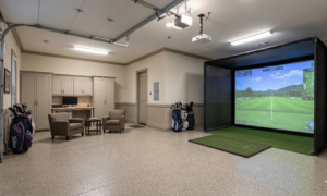 A multi-functional luxury garage conversion in Seminole, Florida, featuring a professional golf simulator bay, an integrated home office desk, and a lounge area with epoxy flooring.