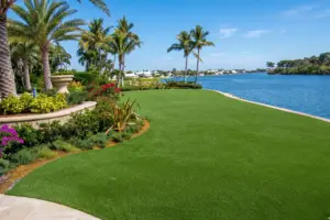 Madeira-Beach-FL-Total-Grass-Replacement-Turf - Sims & Greens Residential artificial turf backyard replacement for a waterfront home in Madeira Beach, Florida, featuring a composite deck and sunset views.