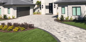 A modern home featuring a paved driveway surrounded by lush, green fake grass in St. Petersburg, FL.