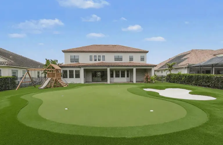 Custom backyard synthetic putting green with a professional sand bunker and chipping fringe at a luxury residential home in Westchase, FL.